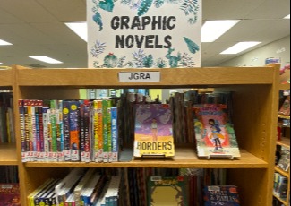 Graphic novels and comic books displayed on a shelf.